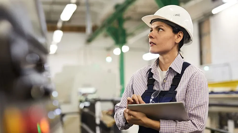 Safety Management Solution Hero. Woman in hard hat with tablet in factory